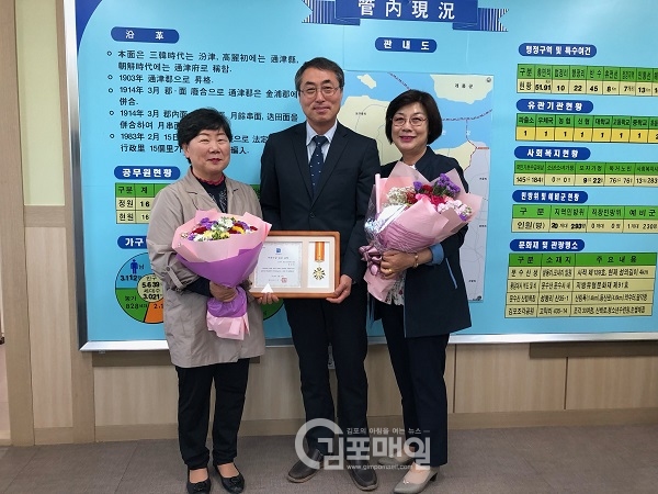 박만준 면장이 효행상을 수상한 정응현씨에게 꽃다발을 전달하고 기념사진을 찍고 있다.