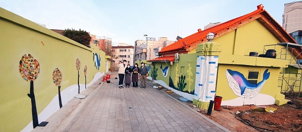 김포 통진읍 청사초롱길 골목 담벼락에 그려낸 벽화를 감상하고 있는 젊은 청년들이 얘기를 나누고 있다.(사진=통진읍제공)&#160;